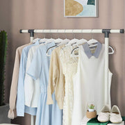 White coat hangers holding shirts, a striped dress and a cardigan on a clothes rail