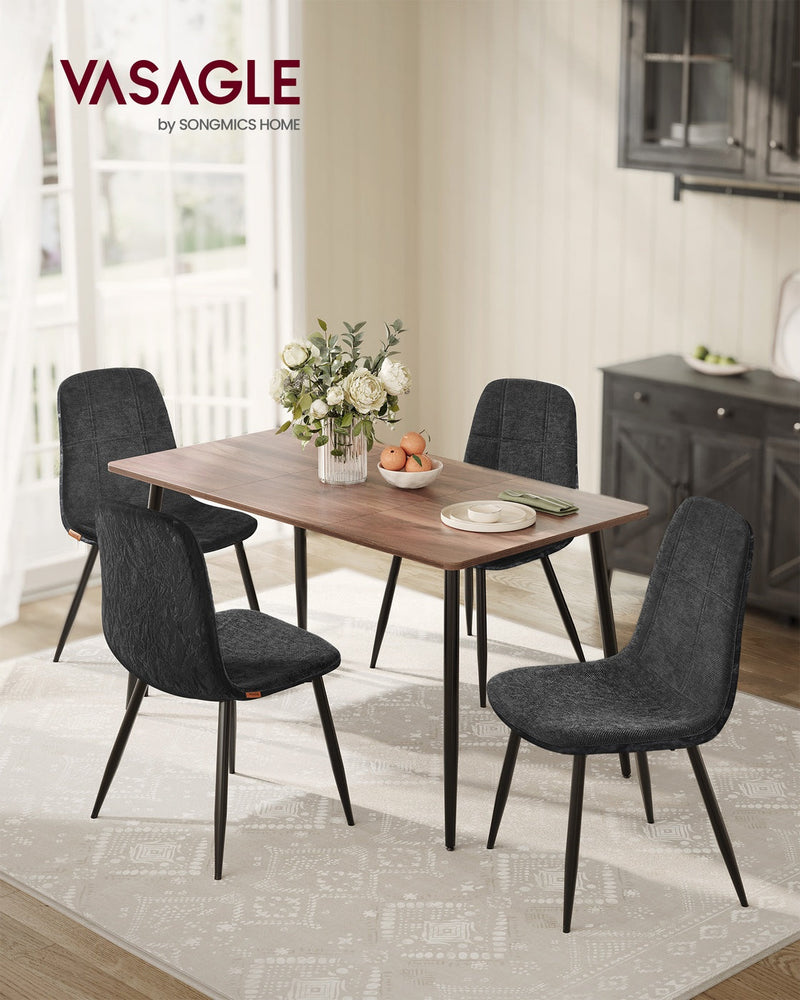 4 slate grey dining chairs around a wooden dining table with a dark sideboard behind