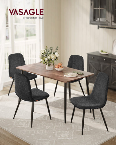 4 slate grey dining chairs around a wooden dining table with a dark sideboard behind