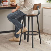 Person standing beside a brown bar stool at a kitchen counter showing the leg base