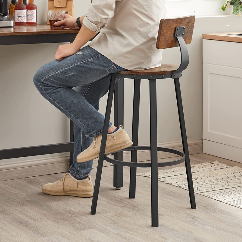 Person standing beside a brown bar stool at a kitchen counter showing the leg base