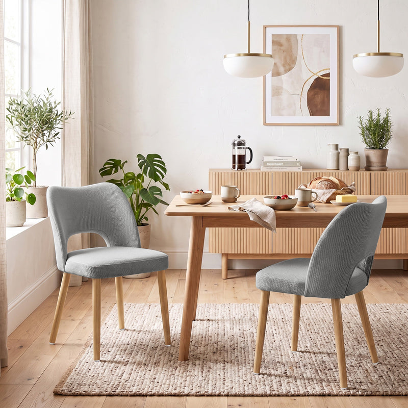 Grey chenille dining chairs at a wooden table in a bright dining room