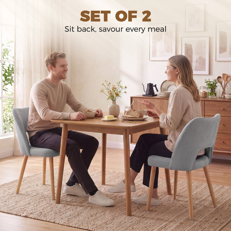 Couple eating at a wooden dining table with grey chenille chairs
