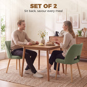 Couple eating at a wooden dining table with green chenille chairs