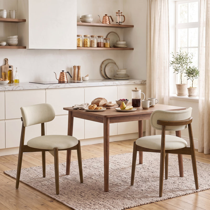 Two beige chenille dining chairs at a wooden kitchen table in a bright room