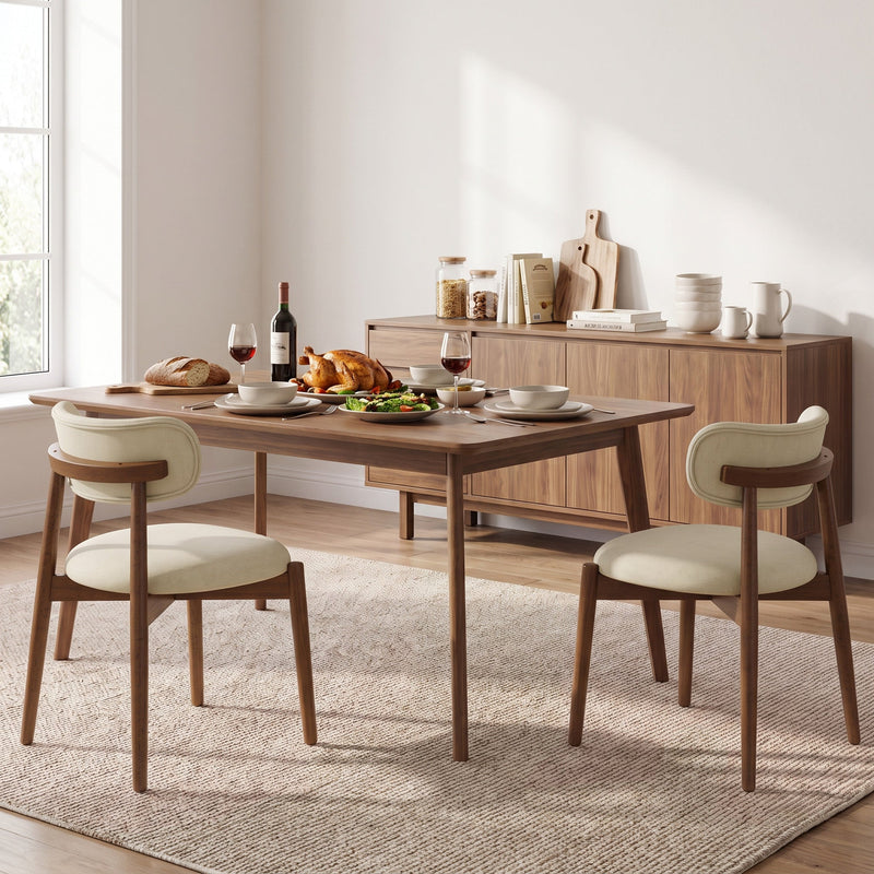 Two beige dining chairs at a laid table beside a wooden sideboard