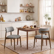Two grey chenille dining chairs at a wooden kitchen table in a bright room