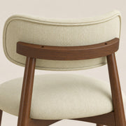 Close-up of the beige chenille seat and curved backrest on a wooden frame