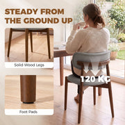Woman sitting on a grey dining chair with solid wood legs, foot pads and a 120 kg weight label