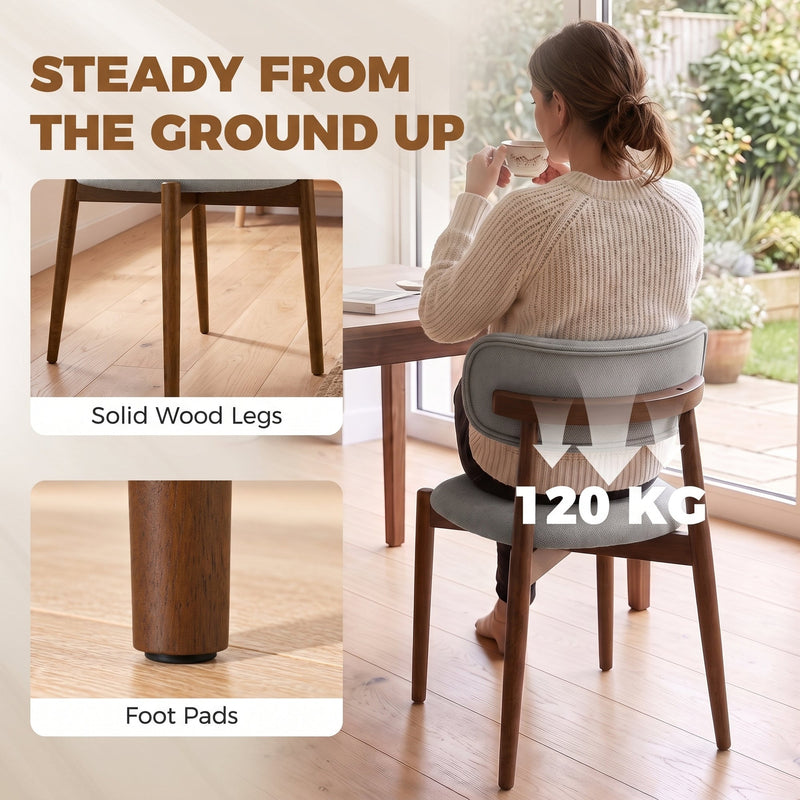 Woman sitting on a grey dining chair with solid wood legs, foot pads and a 120 kg weight label