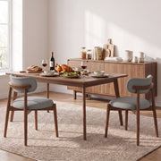 Two grey dining chairs at a laid table beside a wooden sideboard