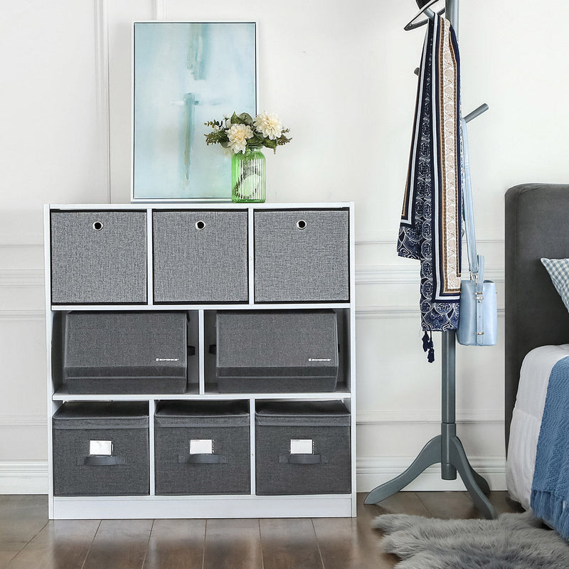 Grey lidded boxes on the middle shelf of a white cube unit in a bedroom