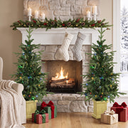 Two Aspen Fir Christmas trees either side of a stone fireplace with stockings