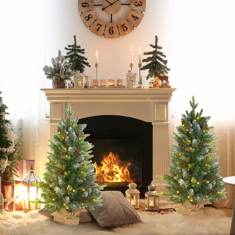 3ft pair of pre-lit Christmas trees by a fireplace mantel with candles and a lit fire