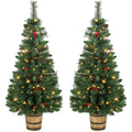 Pair of pre-lit pine Christmas trees with red berries in barrel-style pots
