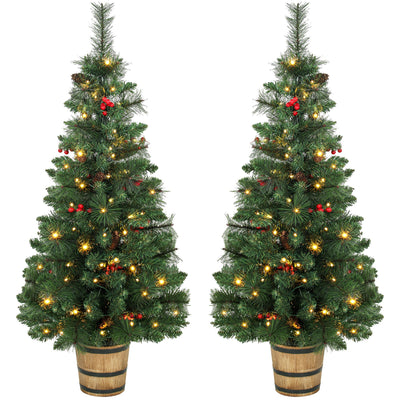 Pair of pre-lit pine Christmas trees with red berries in barrel-style pots