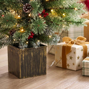 Close-up of frosted pine tips with pine cones, red berries and lights above a rustic pot