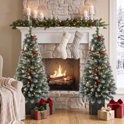 Two frosted pine trees either side of a stone fireplace with stockings