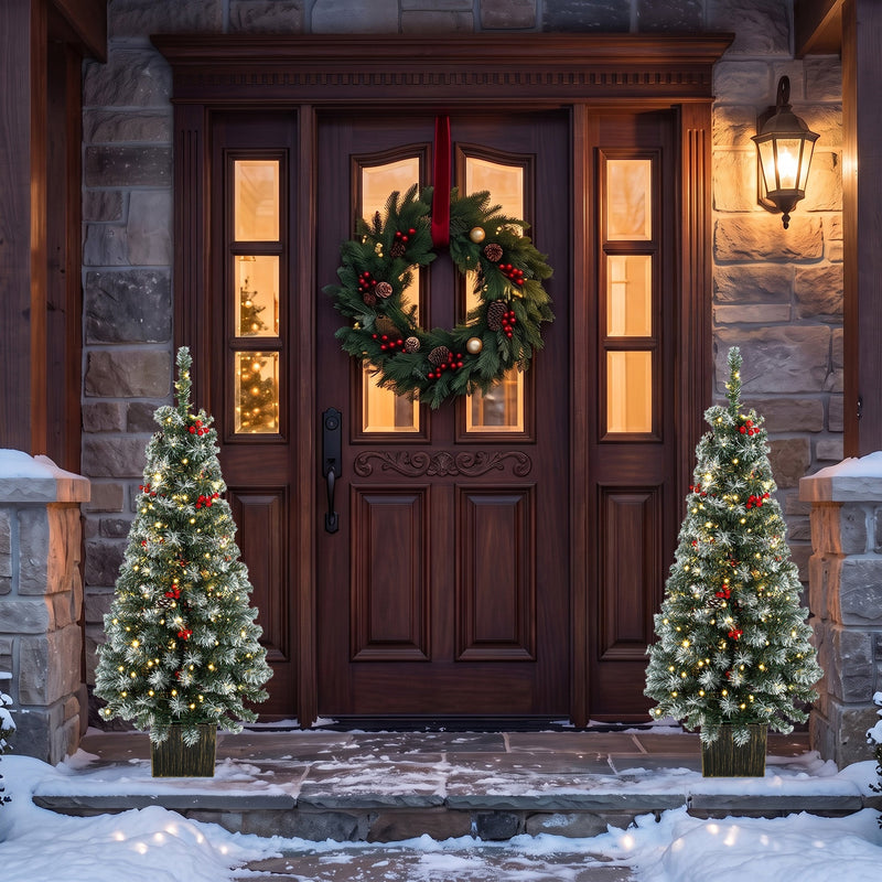 Two frosted pine trees either side of a dark wooden front door with a wreath