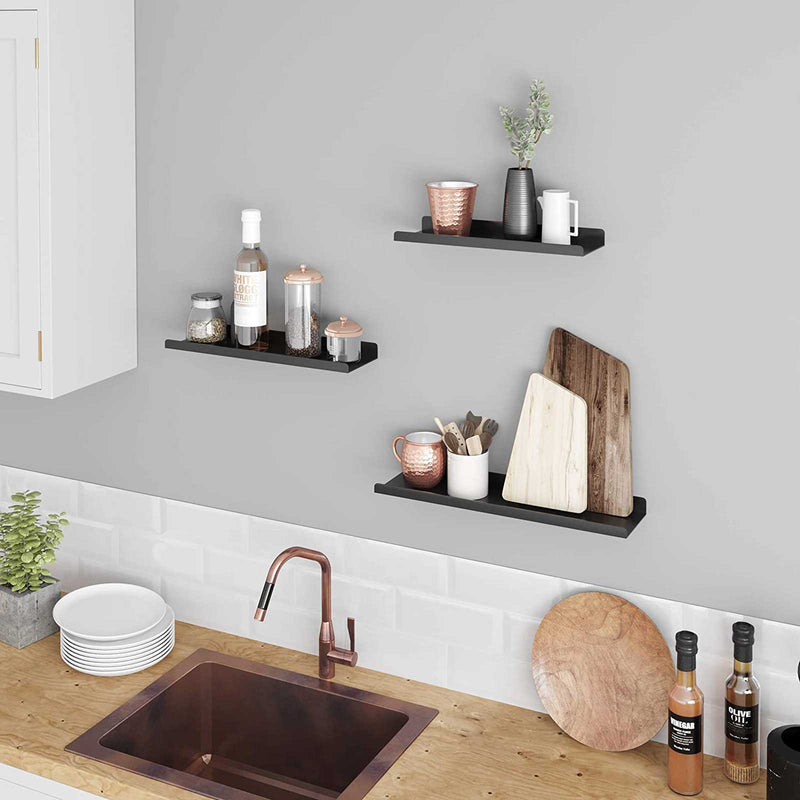 Black wall shelves above a kitchen worktop holding jars, cups and chopping boards