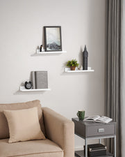 White ledge shelves on a living room wall above a beige armchair and side table