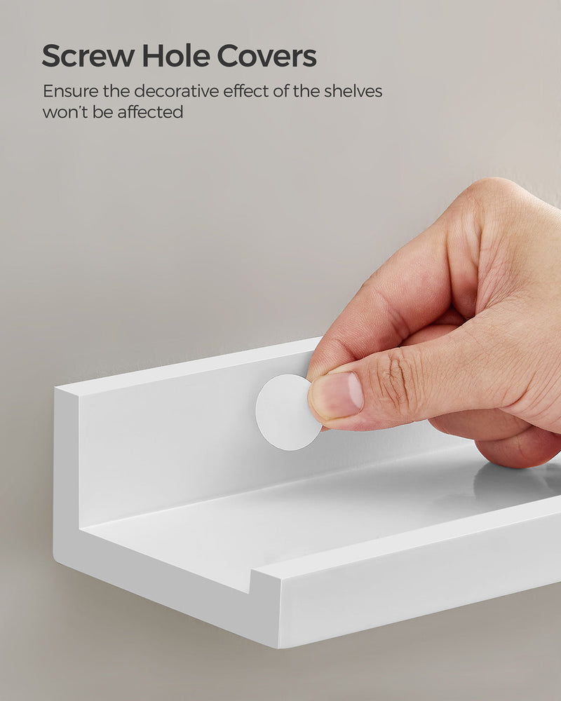 Hand fitting a white cover over the screw hole on the mounted ledge shelf