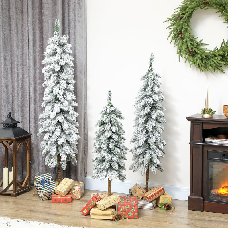 Three flocked pencil trees beside a fireplace with a lantern and gifts