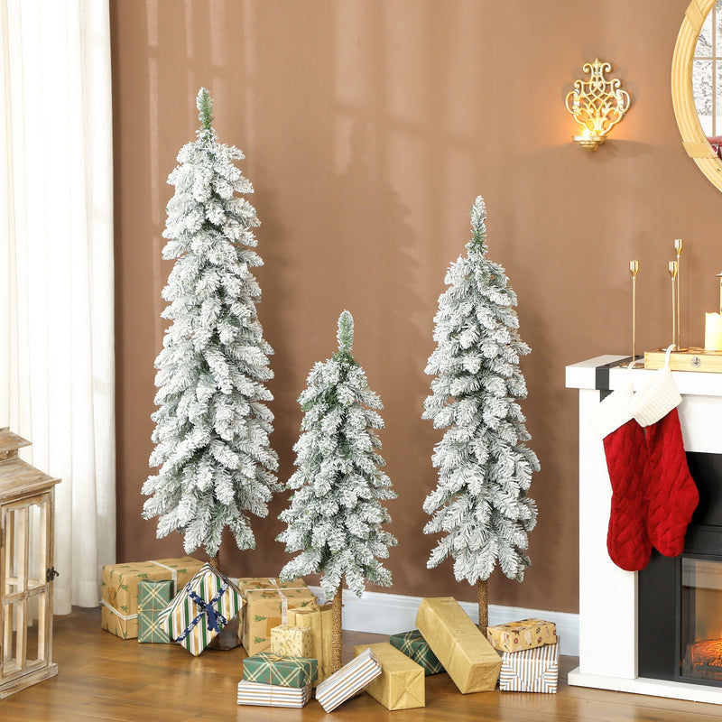 Three flocked pencil trees in front of a fireplace with wrapped gifts