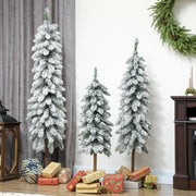 Three flocked pencil trees by grey curtains with a wreath and wrapped gifts