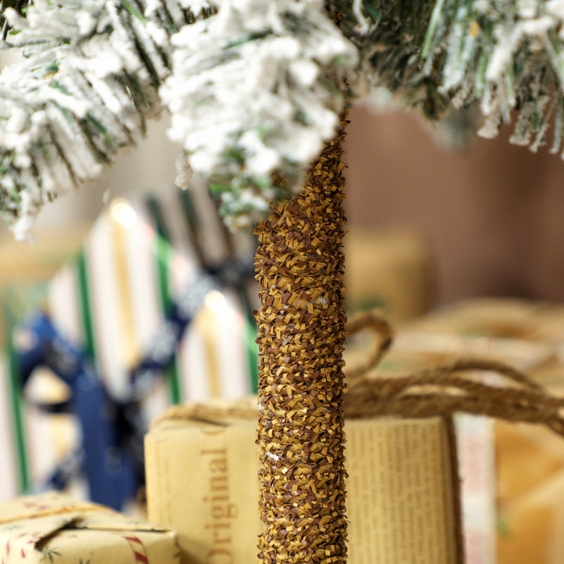 Close-up of the wrapped trunk and flocked lower branches above gifts