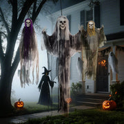 Three hanging skeleton decorations displayed near a tree in a misty garden at dusk