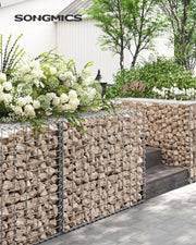 Stone-filled gabion wall edging a garden path beside white flowering shrubs