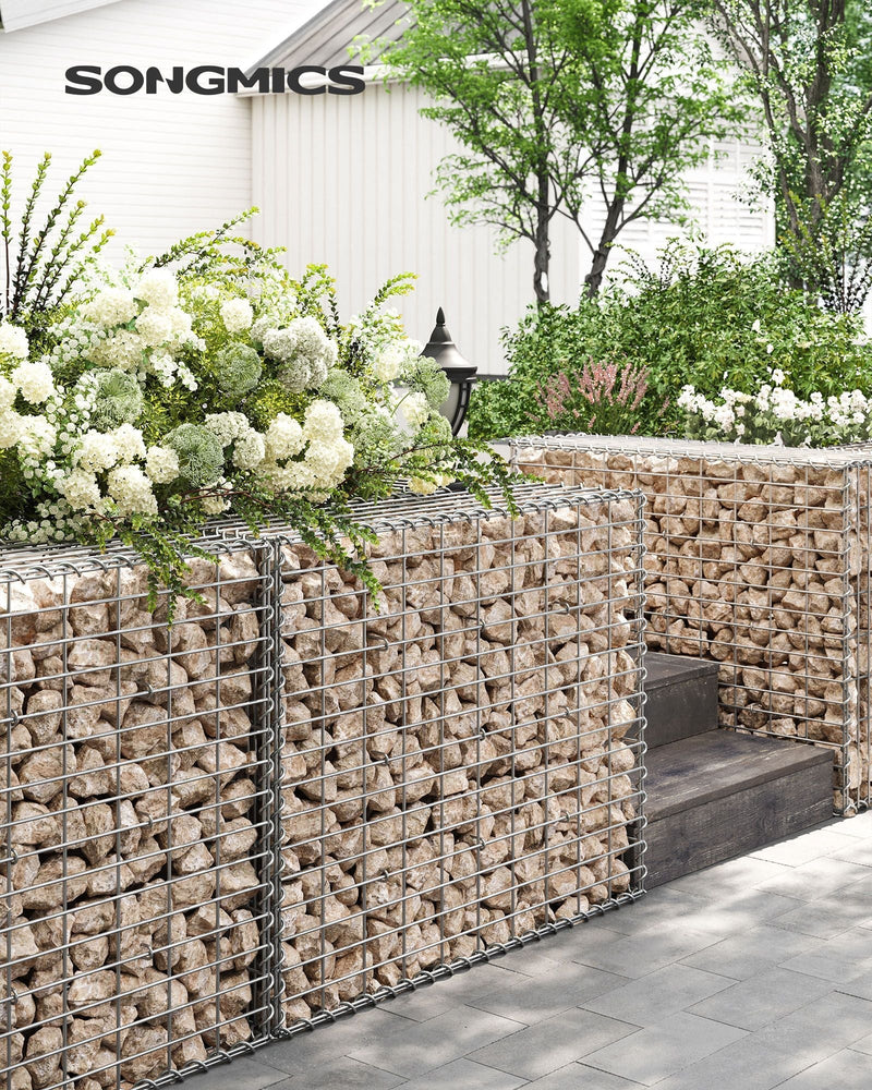 Stone-filled gabion wall edging a garden path beside white flowering shrubs