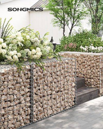 Stone-filled gabion wall edging a garden path beside white flowering shrubs