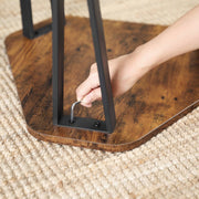 Close-up of the black metal leg fixing under a hexagonal tabletop on a woven rug