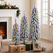 Three flocked multicolour Christmas trees by a fireplace with wrapped gifts