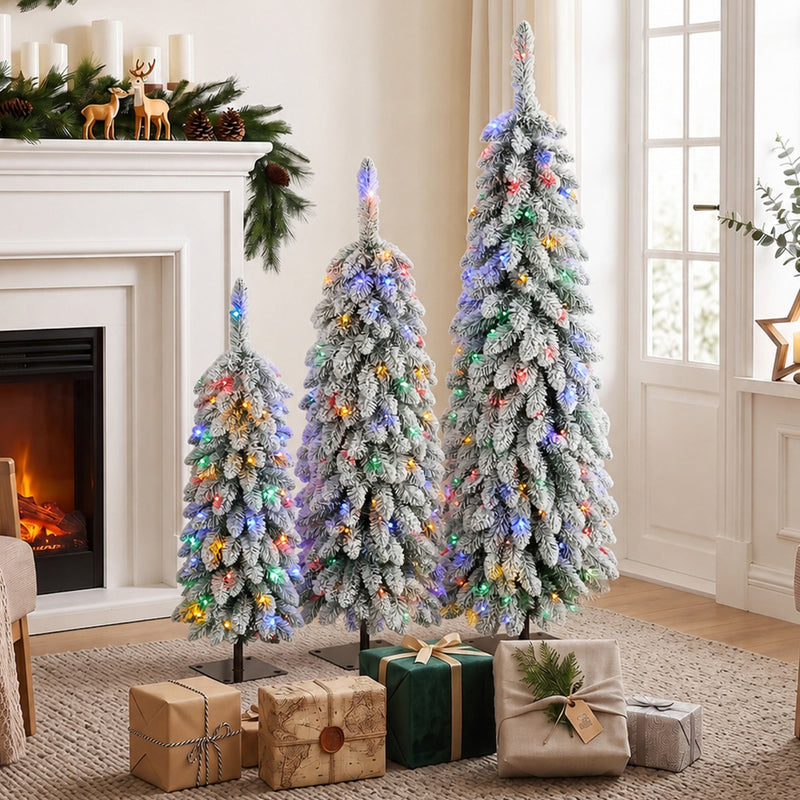 Three flocked multicolour Christmas trees by a fireplace with wrapped gifts