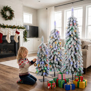 Child hanging a bauble on the multicolour lit trees beside a fireplace