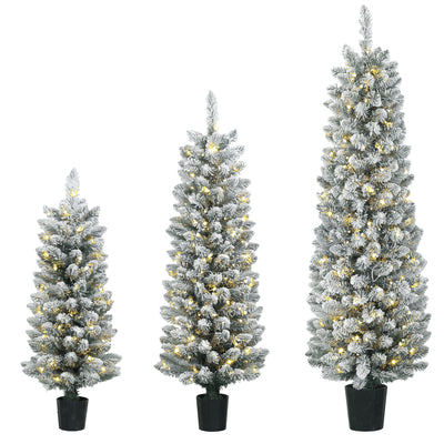 Set of 3 snow-flocked pre-lit Christmas trees in black pots on a white background