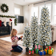 Child hanging a bauble on the lit trees beside a fireplace with stockings