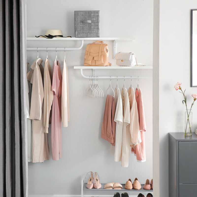 White velvet hangers holding clothes on an open wardrobe rail with shelves above