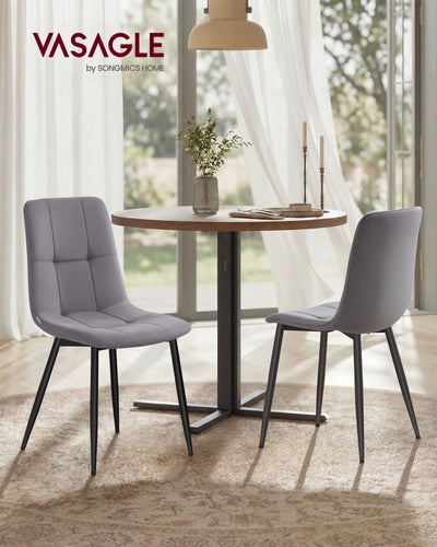 Two Vasagle velvet dining chairs at a round dining table in a lifestyle setting