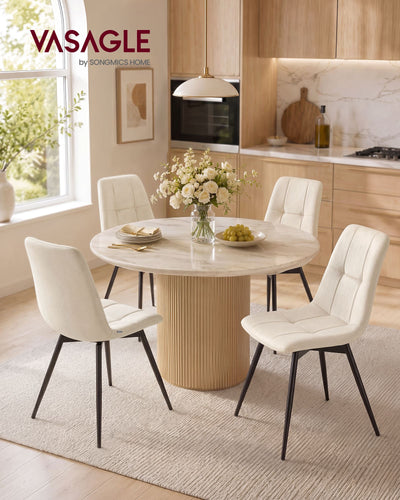 Four light beige velvet dining chairs around a round table in a bright kitchen