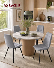 Four grey velvet dining chairs around a round table in a bright kitchen