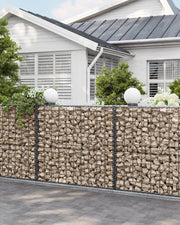 Stone-filled gabion wall running alongside a house exterior