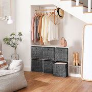 Fabric storage cubes under a hallway clothes rail with one box open showing folded clothes