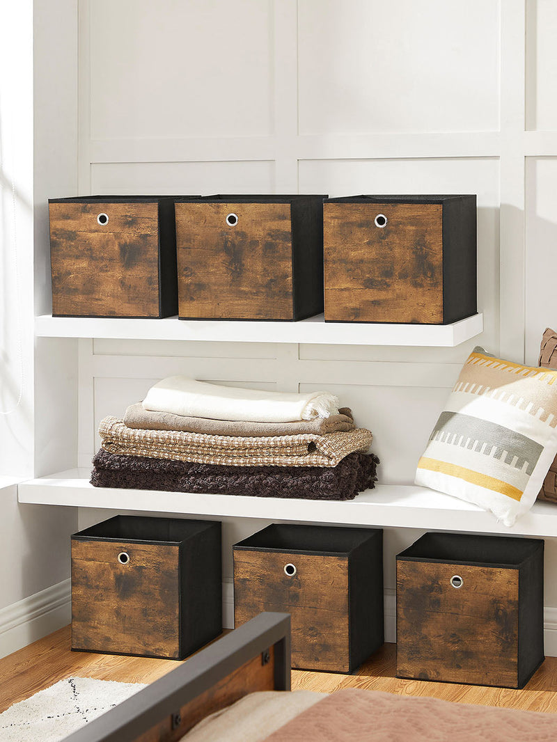 Six cubes lined up along two white alcove shelves beside folded blankets