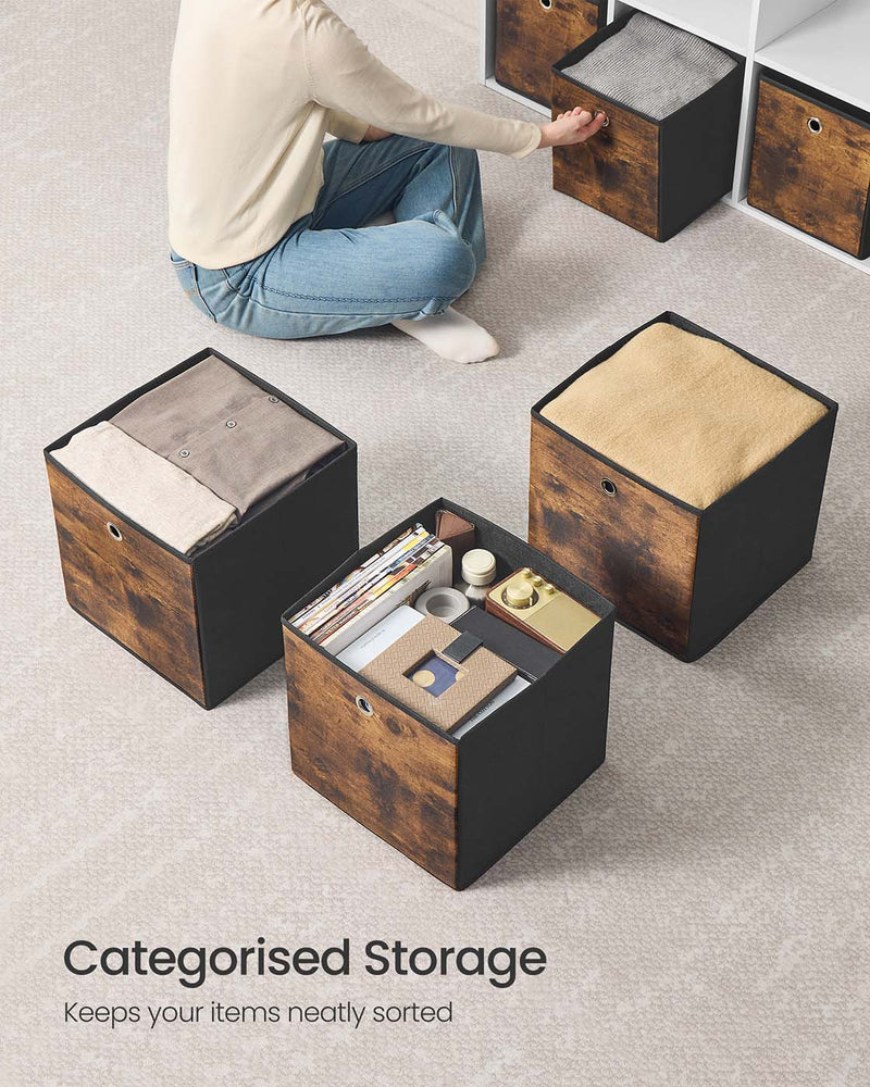Three open storage cubes on a carpet holding folded blankets and desk items