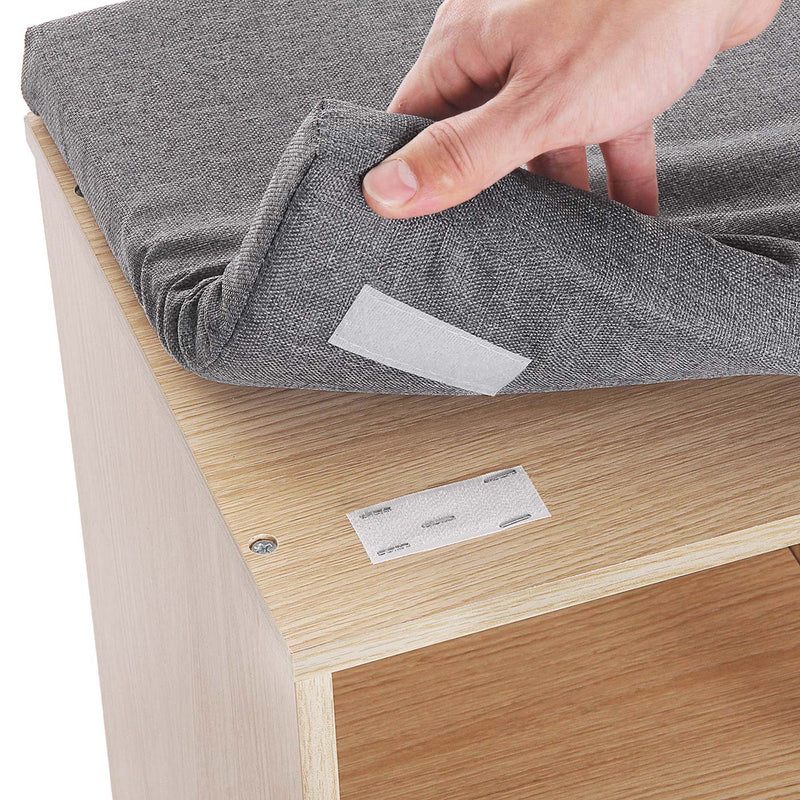 Hand lifting the grey seat cushion off the natural wood bench top to show the fastening