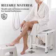 Woman in a robe sitting on the white shower stool shaving her leg, with mould and corrosion resistant callout